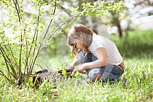 Kid girl with magnifying glass explores grass