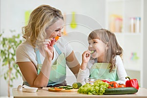 Kid girl and mother eating healthy food vegetables