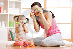 Kid girl and mother have a fun with puzzle toys. Young woman and child toddler sitting on floor and playing educational