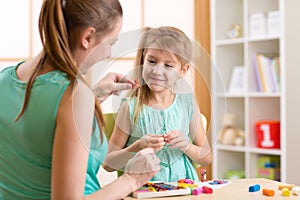 Kid girl and mother play colorful clay toys at