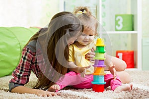Kid girl and mother playing with cup toys