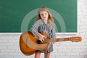 Kid girl on musik lesson at school. Elementary school child hold guitar in class.