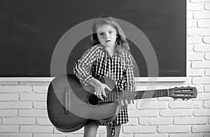 Kid girl on musik lesson at school. Elementary school child hold guitar in class.