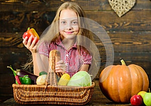 Kid girl near basket full of fresh vegetables harvest rustic style. Farm market fall harvest. Child girl presenting