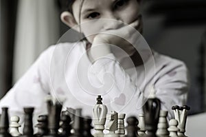 Kid girl playing chess, looking at chess board and thinking about her next move