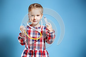 Kid girl playing doctor with syringe and stethoscope on a blue background.