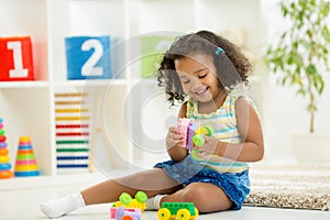 Kid girl playing toys at kindergarten room photo