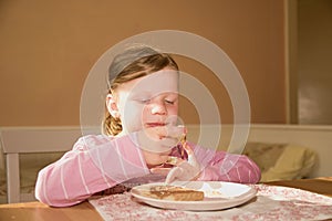 Kid girl playlful eats chocolate cream spread on bread. Chocolate sweet food snack. Happy girl has a snack in the