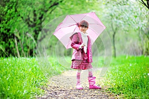 Kid girl posing outdoors with pink umbrella