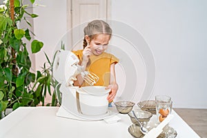 kid girl prepares dough in submersible mixer and it tastes unpalatable