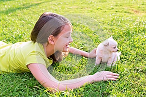 Kid girl and puppy dog happy lying in lawn