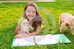 Kid girl and puppy dog at homework lying in lawn