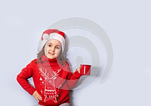 kid girl in red Santa\'s hat holding red mug or cup empty copy space for design or text. Banner. Christmas mockup