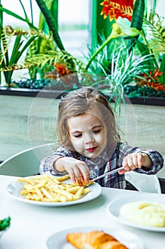 Kid girl in a restaurant eating fast food.