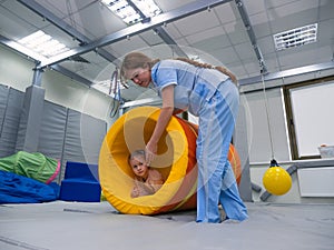 Kid girl rotation in roller tonnel during sensory integration session