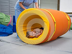 Kid girl rotation in roller tonnel during sensory integration session