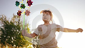 kid girl run after a pinwheel toy in a beautiful city park. kid girl fun run and playing in the park. Adventures in the