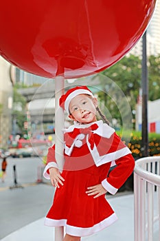 Kid girl in Santa hat having fun at Christmas time. Merry Xmas background