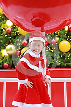 Kid girl in Santa hat having fun at Christmas time. Merry Xmas background