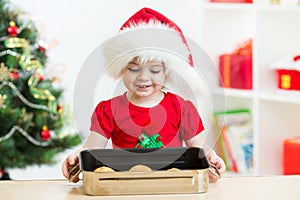 Kid girl in Santa hat holding Christmas cookies