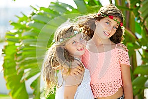 Kid girl sisters hug banana tree leaves bright day