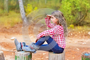 Kid girl sitting in forest trunk looking far away