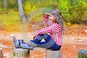 Kid girl sitting in forest trunk looking far away