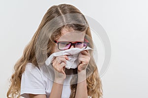 Kid girl sneezes in handkerchief. Flu season, white backgroud, copy space. photo