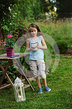 kid girl walking with candle holder in romantic evening garden