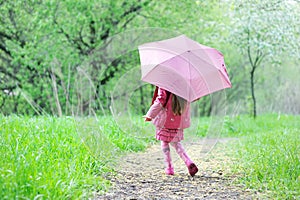 Kid girl walking outdoors with pink umbrella