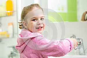 Kid girl washing hands in bathroom