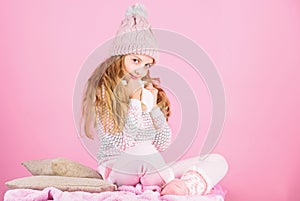 Kid girl wear knitted warm hat relaxing pink background. Winter fashion warm clothes concept. Warm accessories that will