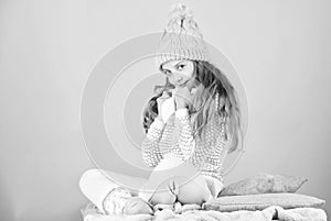 Kid girl wear knitted warm hat relaxing pink background. Winter fashion warm clothes concept. Warm accessories that will