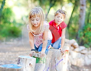 Kid girls playing on trunks in forest nature photo