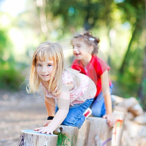 Kid girls playing on trunks in forest nature