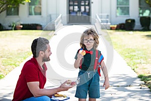 Kid going to primary school. Cute schoolboy eating outdoors the school from lunch boxe. Healthy school breakfast for