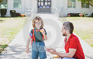 Kid going to primary school. Cute schoolboy eating outdoors the school from lunch boxe. Healthy school breakfast for