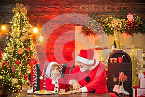 Kid grandson and grandfather in Santa Hat Writing Wish List - unfocused lights background. Family write letter to Santa.