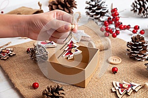 Kid hand drop a small decorative Christmas tree into the gift box