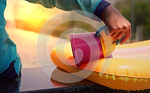 Kid hand plays water pouring on poolside in swimming pool with sun light in summer vacation time,closed up