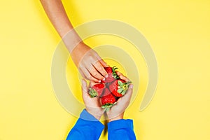 Kid hand taking strawberry from another child`s hands