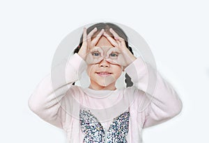 Kid with hands glasses in front of her eyes isolated on white background. Little asian girl looking through imaginary binocular