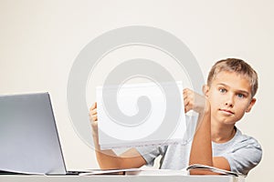 Kid hands holding open notebook with blank white pages Boy sitting at table with books and laptop computer