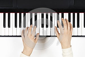 Kid hands learning to play on the piano. Top view