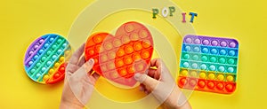 Kid hands playing with colorful pop It fidget toy. Colorful antistress sensory toy fidget push pop it.