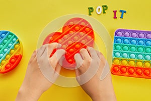 Kid hands playing with colorful pop It fidget toy. Colorful antistress sensory toy fidget push pop it.