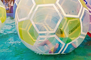 Kid having fun in giant bubble ball on water in the swimming pool at the theme park