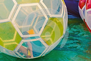 Kid having fun in giant bubble ball on water in the swimming pool at the theme park