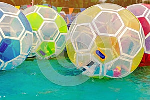 Kid having fun in giant bubble ball on water in the swimming pool at the theme park