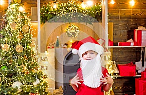 Kid having fun near Christmas tree indoors. Happy child with white beard. Christmas Celebration holiday. Happy little